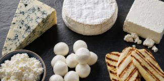 Erkennst du diese 10 Käsesorten? Auswahl verschiedener Käsesorten von Blauschimmel bis Hüttenkäse auf dunklem Schiefer