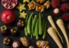 Erkennst du diese 10 Lebensmittel? Exotische Früchte und Gemüse wie Granatapfel, Sternfrucht, Rambutan und Okra auf dunklem Schiefer angeordnet