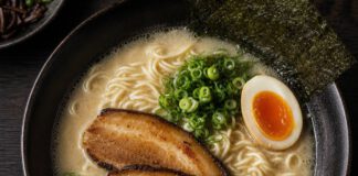Wie schmeckt Ramen? Schale Ramen von oben mit trüber heller Brühe, gewellten Nudeln, Schweinebauchscheiben, halbem Ei, Frühlingszwiebeln und Nori