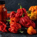 Leuchtend rote und orange Chilischoten mit knubbeliger Oberfläche auf einer Schieferplatte