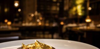 Kann man Blattgold essen? Dunkles Schokoladendessert auf weißem Teller, belegt mit glänzendem essbarem Blattgold