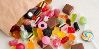 Tag der Süßigkeiten am 4. November: Herkunft und Zuckerfrage Bunte Bonbons, Gummibärchen, Lakritz, Schokoladenstücke und Lutscher auf einem hellen Tisch verstreut