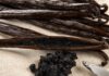Was ist Bourbon-Vanille? Dunkle glänzende Vanilleschoten auf Leinen, eine längs aufgeschlitzt mit sichtbarem schwarzem Mark, daneben ausgekratztes Vanillemark und ein Messer