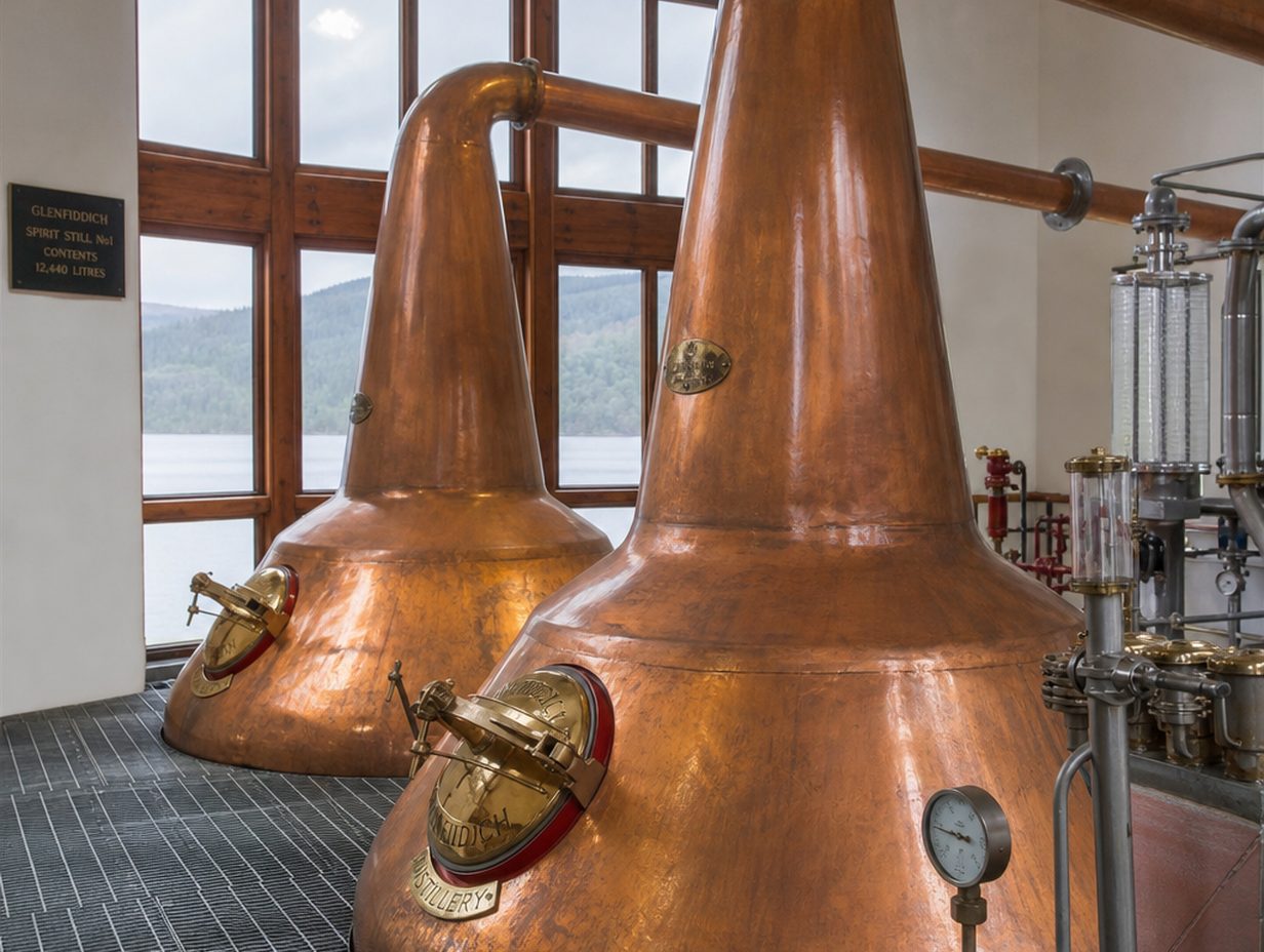 Zwei große kupferne Pot Stills mit geschwungenen Hälsen in einer traditionellen Destillerie