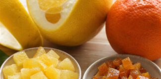 Orangeat und Zitronat: Was ist der Unterschied? Zwei Schalen nebeneinander, links helle Würfel Zitronat, rechts bräunlich-orange Würfel Orangeat, dahinter eine dickschalige Zitrusfrucht und eine Orange
