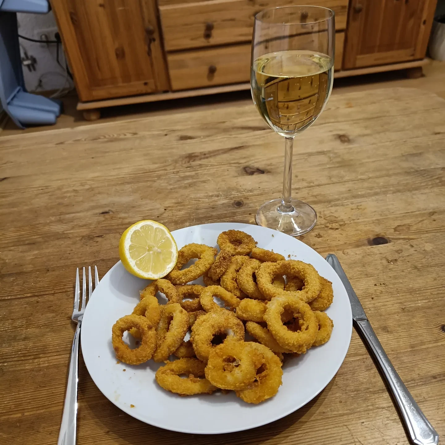 Frittierte Calamari-Ringe mit einer halben Zitrone auf einem weißen Teller