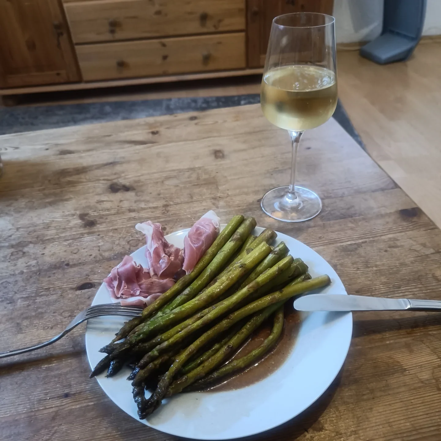 Gebratener grüner Spargel mit luftgetrocknetem Rohschinken auf einem Teller