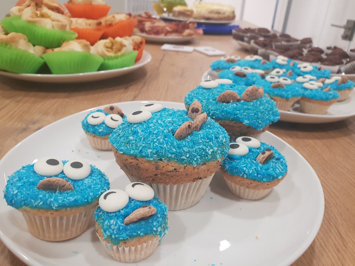 Muffins mit blauem Kokosstreusel-Topping, Zuckeraugen und Keksstück als Krümelmonster dekoriert