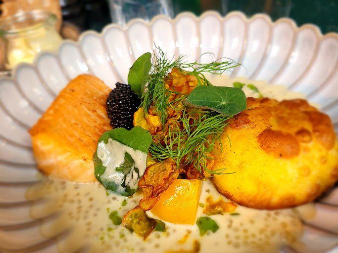 Gegartes Lachsfilet mit Kaviar, Kapuzinerkresse und heller Buttersauce auf einem Teller
