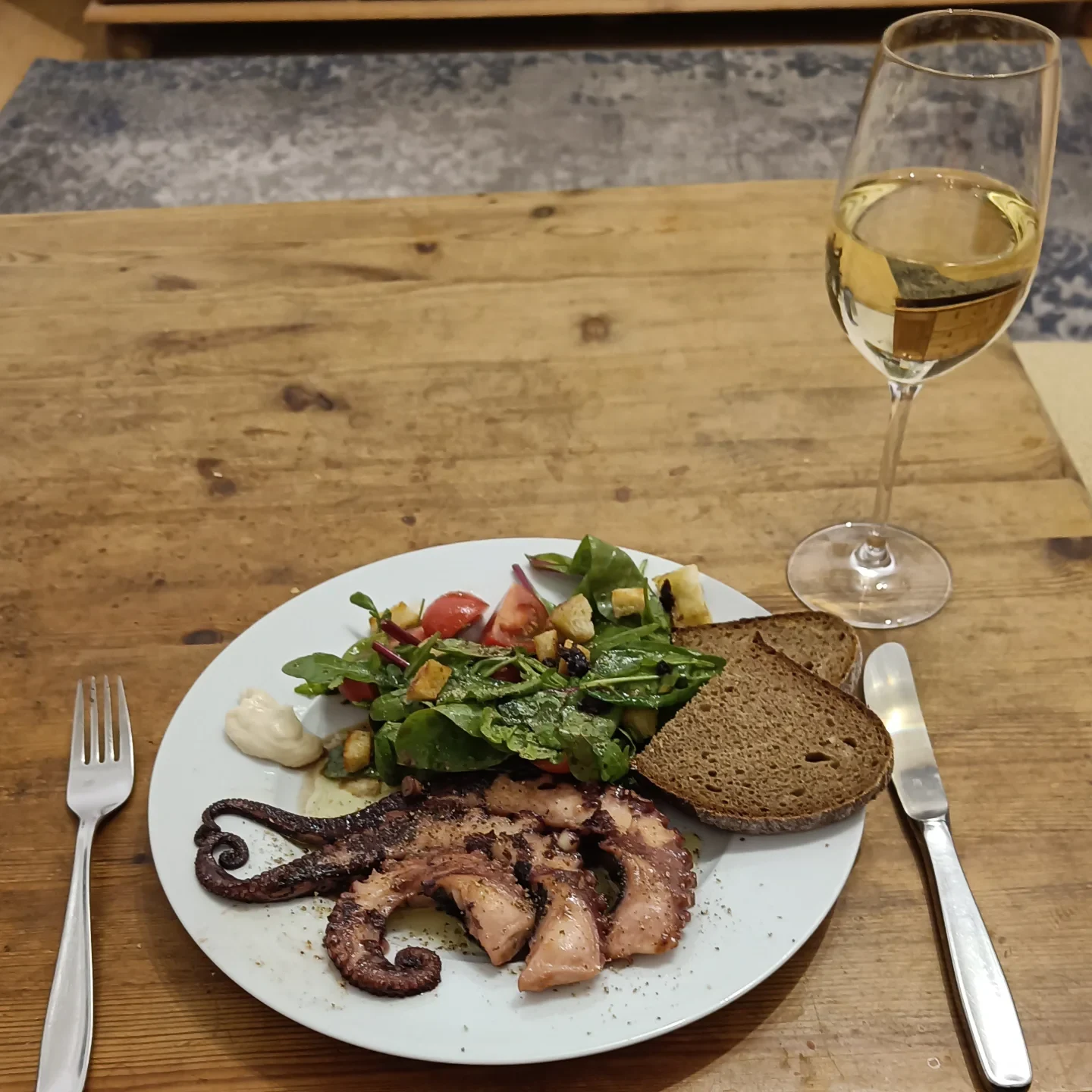 Gegrillte Oktopus-Tentakel mit Blattsalat, Dip und Bauernbrot