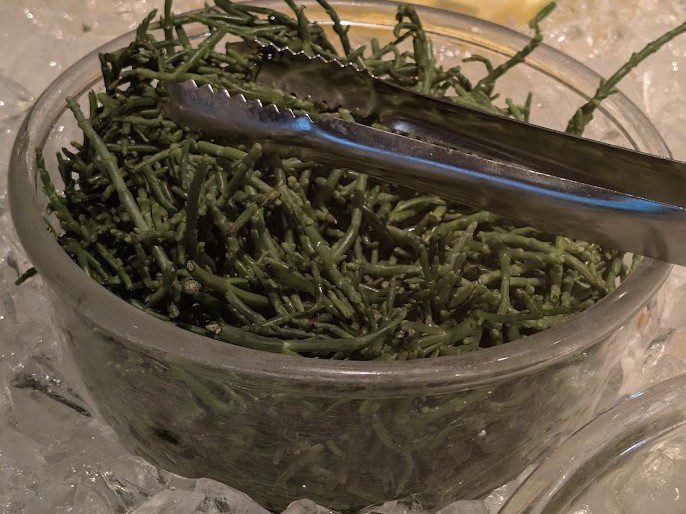 Frischer Queller, auch Meeresspargel genannt, in einer Glasschale auf Eis an einem Buffet
