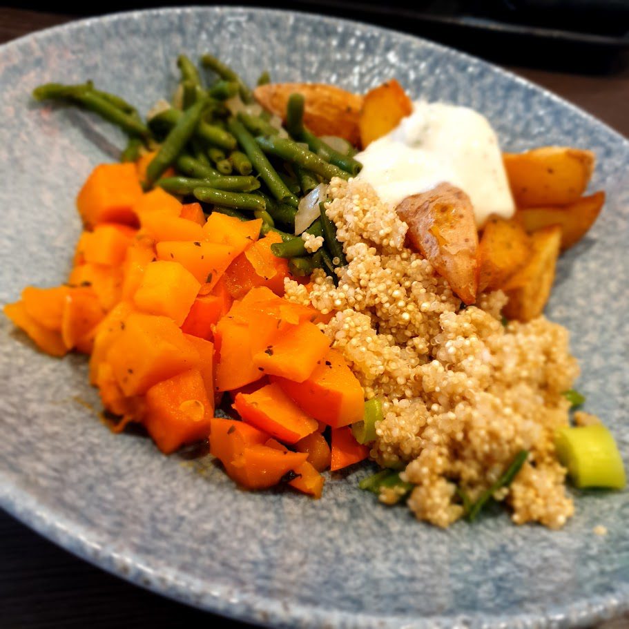 Teller mit Quinoa, Karottenwürfeln, grünen Bohnen, Kartoffelecken und Joghurtdip