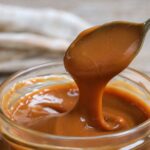 Dulce de leche im Glas mit Löffel