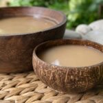 Kava in einer Kokosschale neben der Kavaschüssel
