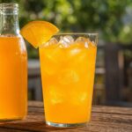 Glas Orangenlimonade mit Eis und Orangenscheibe