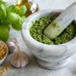 Pesto im Marmormörser mit Basilikum und Pinienkernen
