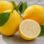Frische Zitronen mit Blättern, eine davon halbiert